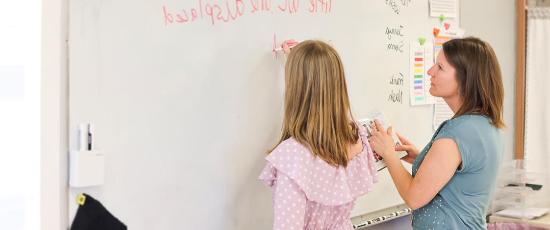 凯伦和一个年轻的学生在教室的白板上写字